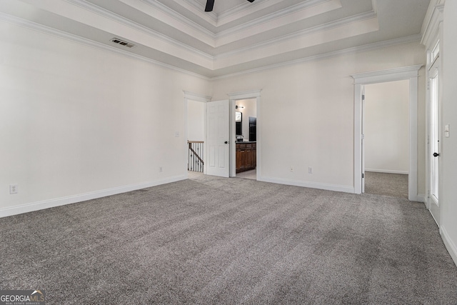 empty room with visible vents, carpet floors, baseboards, crown molding, and a raised ceiling