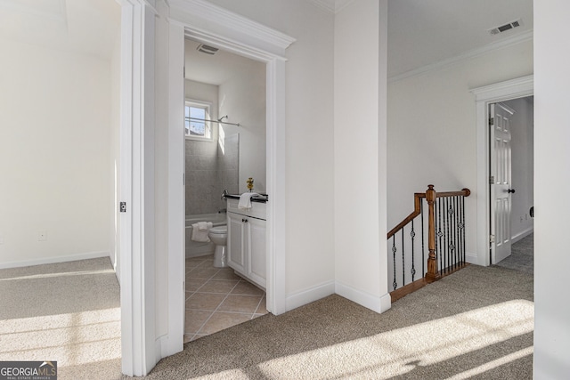 hallway with visible vents, baseboards, ornamental molding, an upstairs landing, and carpet floors