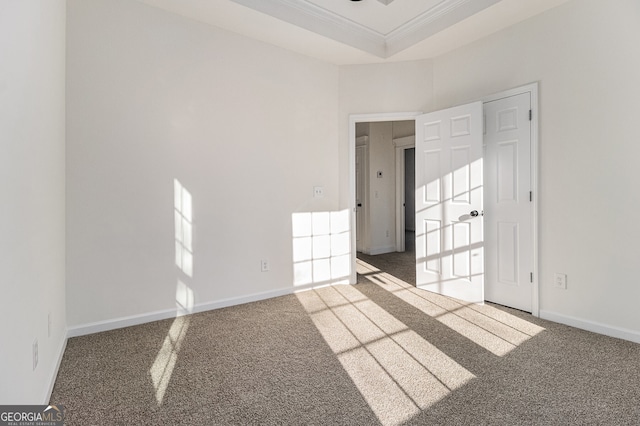 unfurnished room with a tray ceiling, baseboards, carpet floors, and ornamental molding