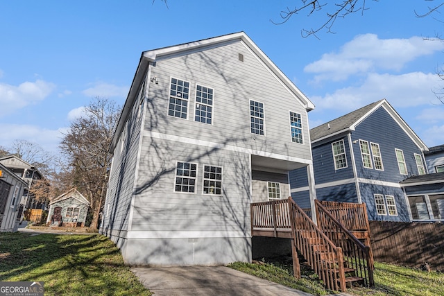back of house featuring a lawn, concrete driveway, and stairs