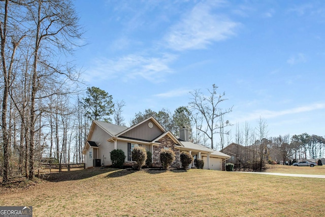 view of front facade with central AC, a front yard, a chimney, stone siding, and an attached garage