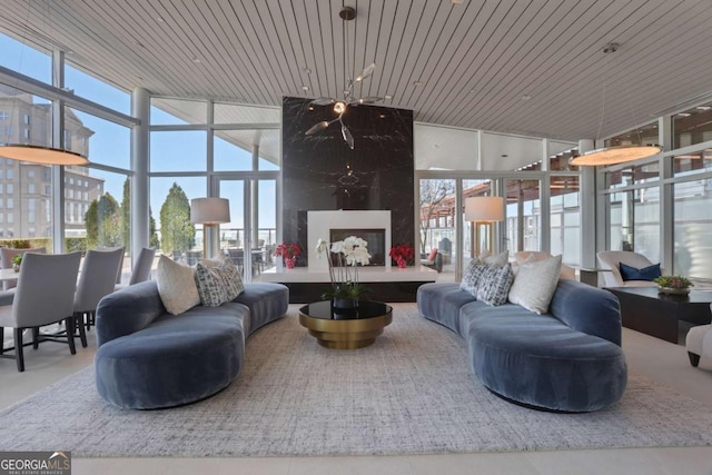 living area featuring a wealth of natural light, wooden ceiling, a fireplace, and a wall of windows