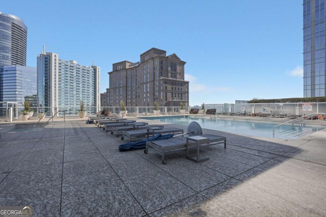 community pool featuring a city view, a patio, and fence