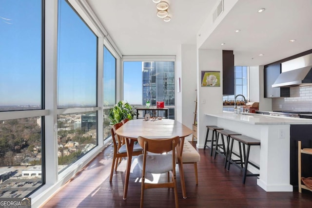 dining space featuring a wall of windows, visible vents, baseboards, and wood finished floors