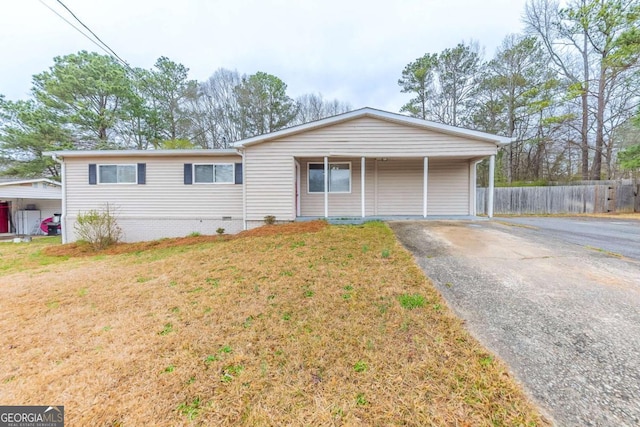 ranch-style house with aphalt driveway, fence, and a front yard