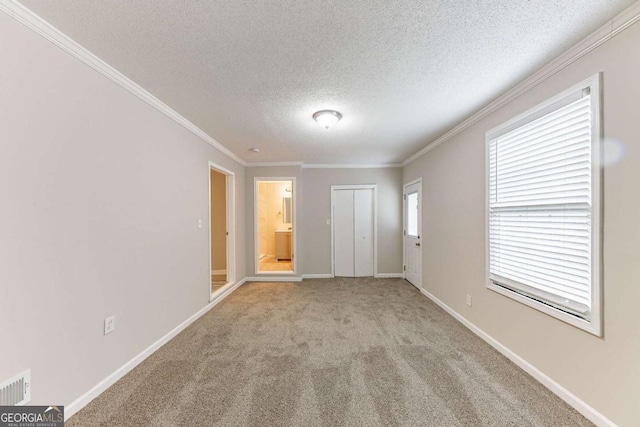 carpeted entryway featuring crown molding, baseboards, visible vents, and a textured ceiling