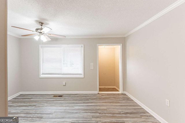 empty room featuring crown molding, wood finished floors, baseboards, and a textured ceiling