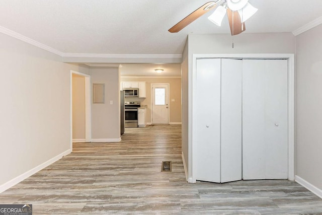 interior space with baseboards, visible vents, light wood finished floors, a closet, and crown molding