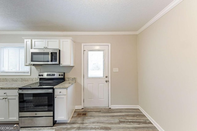 kitchen featuring light wood-style flooring, ornamental molding, a textured ceiling, appliances with stainless steel finishes, and white cabinets