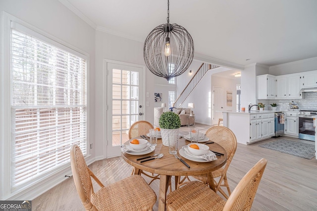 dining room featuring crown molding, light wood-style flooring, baseboards, and a chandelier