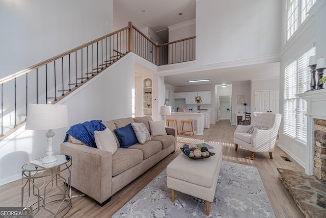 living area featuring plenty of natural light, a fireplace, stairs, and light wood-style floors