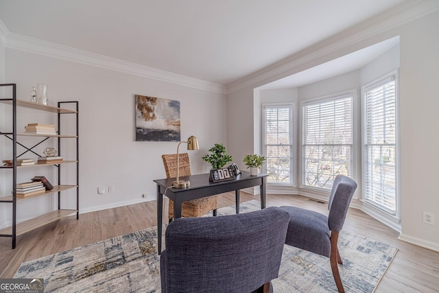 office area with light wood-style floors, baseboards, and ornamental molding