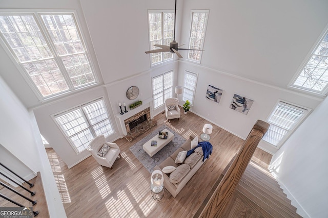 living room with a healthy amount of sunlight, a high ceiling, ceiling fan, and wood finished floors