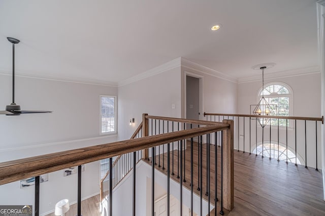 corridor featuring crown molding, an upstairs landing, recessed lighting, an inviting chandelier, and wood finished floors