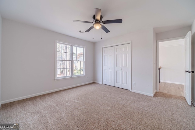 unfurnished bedroom with carpet, visible vents, baseboards, ceiling fan, and a closet