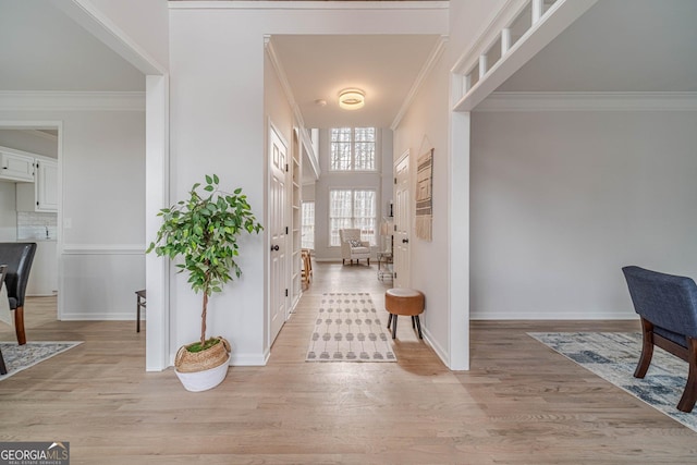 entrance foyer with crown molding, baseboards, and light wood finished floors