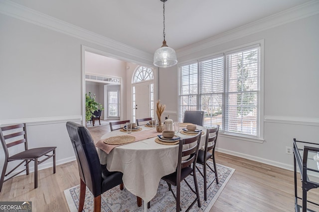 dining room featuring crown molding, light wood-style floors, and baseboards