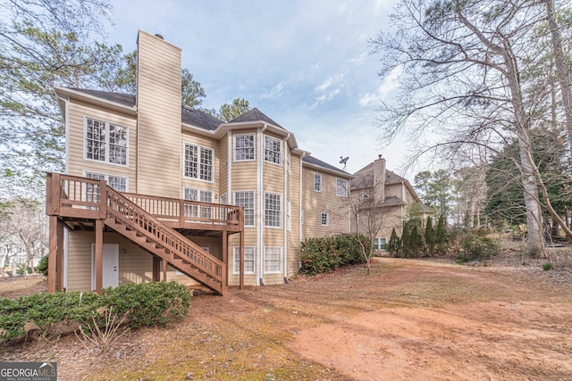 back of property featuring stairway, a wooden deck, and a chimney