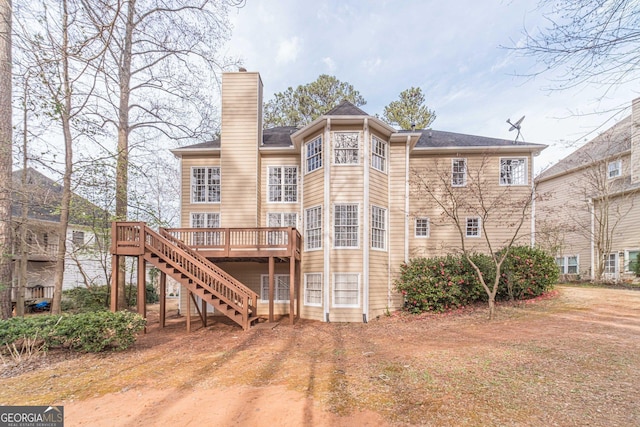 back of house with stairway, a deck, and a chimney