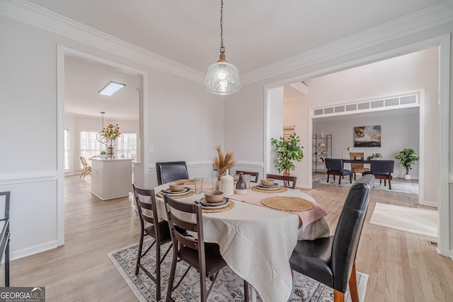 dining space featuring crown molding and light wood-style floors