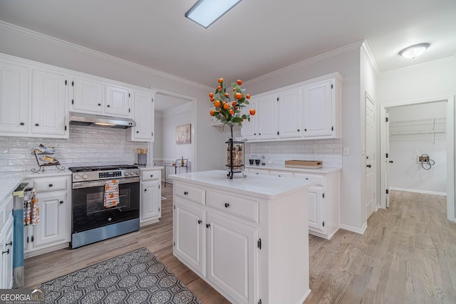 kitchen with under cabinet range hood, light countertops, light wood-style flooring, white cabinets, and stainless steel gas range