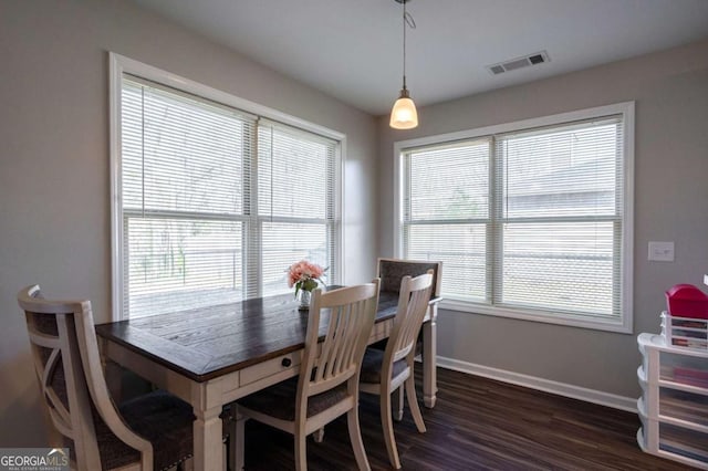 dining room with dark wood-style flooring, baseboards, visible vents, and a wealth of natural light