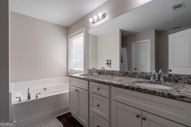 full bath with double vanity, a bath, visible vents, and a sink