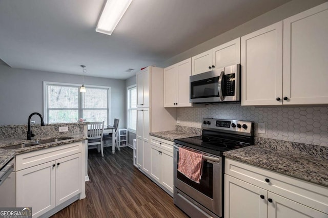 kitchen with a sink, backsplash, appliances with stainless steel finishes, and white cabinetry