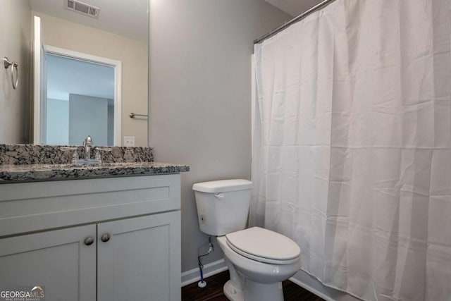 bathroom featuring vanity, wood finished floors, visible vents, baseboards, and toilet