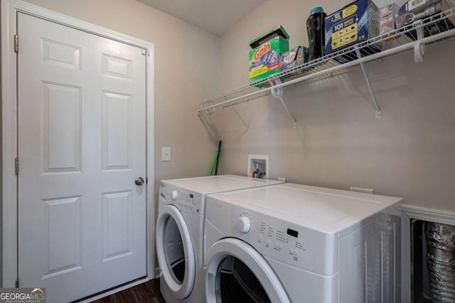 clothes washing area with laundry area, washing machine and dryer, and dark wood-type flooring