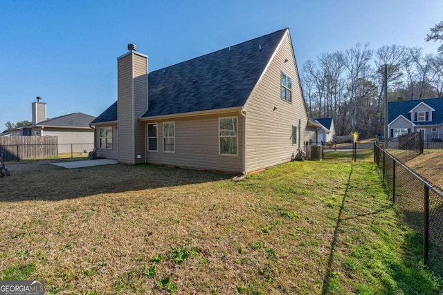 rear view of property featuring a lawn, a patio, a chimney, and a fenced backyard