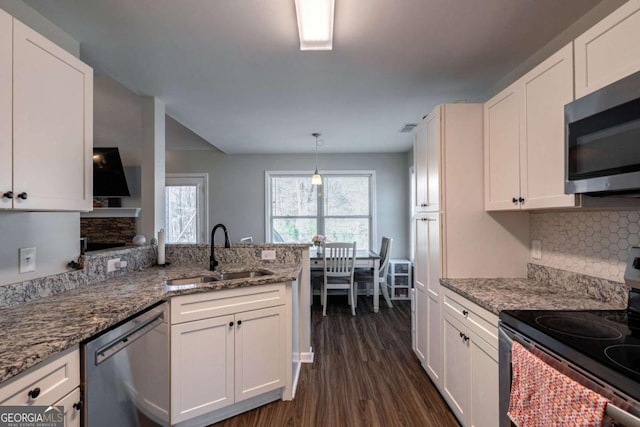 kitchen with dark wood-type flooring, a sink, white cabinetry, stainless steel appliances, and a peninsula