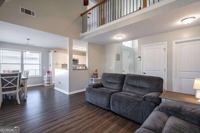 living room with dark wood finished floors, a high ceiling, baseboards, and visible vents