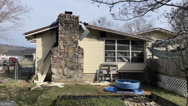 rear view of property featuring a chimney and fence