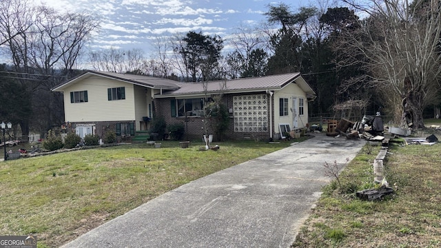 tri-level home with a front yard, brick siding, and metal roof