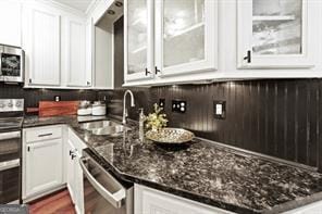 6505 Samoa Way, Flowery Branch, GA 30542 - kitchen with stainless steel appliances, a sink, white cabinets, glass insert cabinets, and dark stone countertops