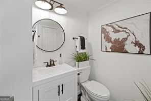 bathroom with toilet, vanity, and crown molding