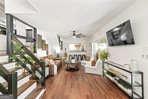 living area featuring stairway, a ceiling fan, and wood finished floors