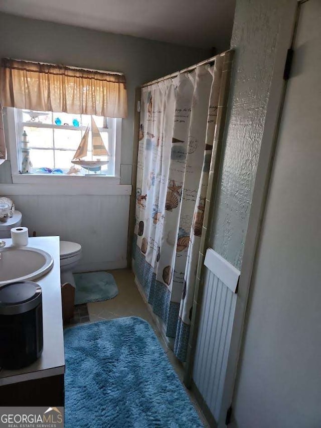 full bathroom with curtained shower, toilet, and vanity