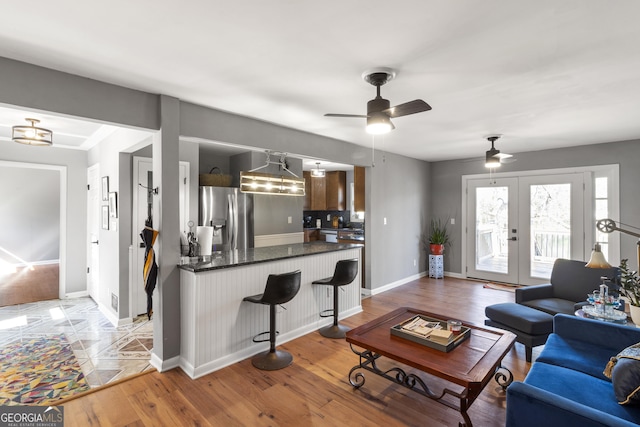 living area with french doors, light wood-type flooring, and baseboards