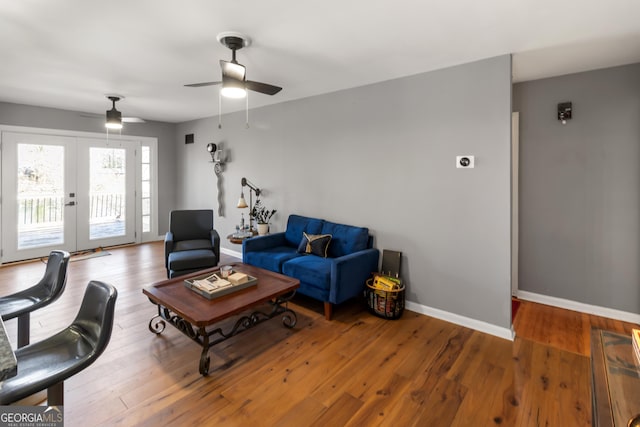 living area with a ceiling fan, wood finished floors, baseboards, and french doors