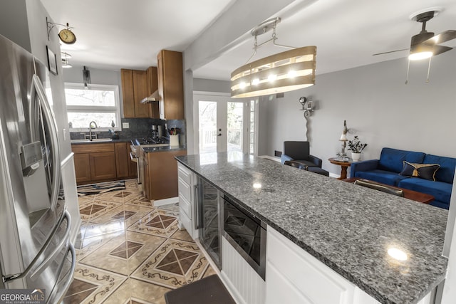 kitchen featuring brown cabinetry, open floor plan, stainless steel appliances, and a sink