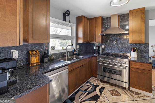 kitchen featuring tasteful backsplash, light tile patterned floors, appliances with stainless steel finishes, wall chimney exhaust hood, and a sink