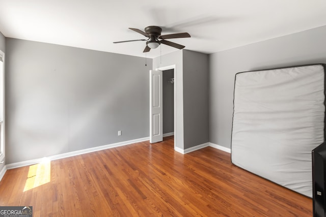 unfurnished bedroom with a ceiling fan, wood finished floors, and baseboards