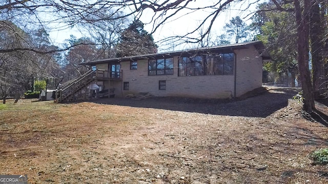 back of property featuring stairs, a wooden deck, brick siding, and a chimney