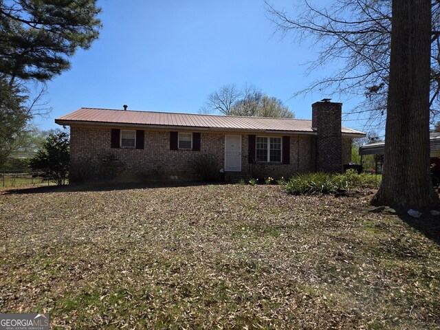 view of front of home featuring metal roof, brick siding, and a chimney