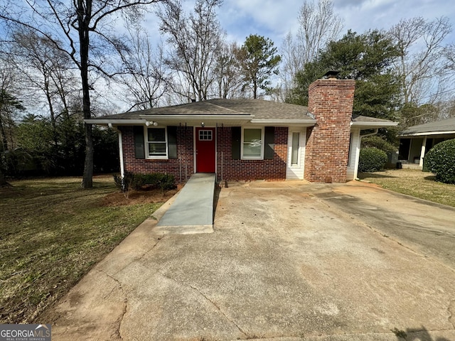 view of front facade with brick siding, driveway, and a chimney