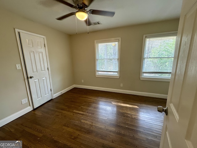 empty room with dark wood finished floors, ceiling fan, and baseboards