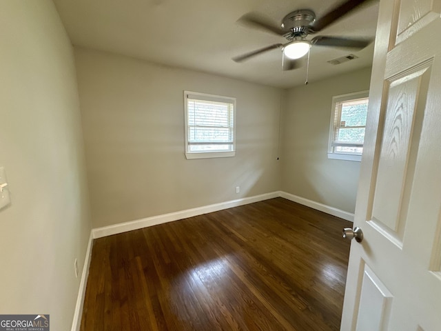 empty room featuring visible vents, a ceiling fan, baseboards, and dark wood-style flooring