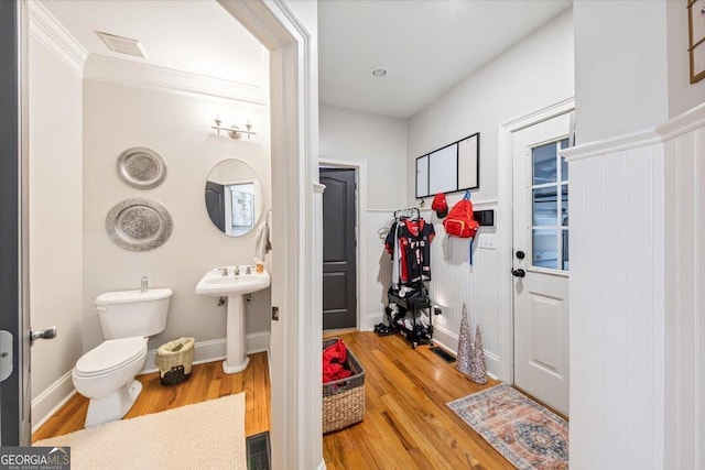 half bath featuring toilet, wood finished floors, visible vents, and a sink